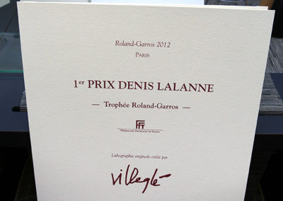 Une authentique pièce muséale : le portfolio du 1er Prix Denis-Lalanne-Trophée Roland-Garros ! Un Prix résolument francophone, créé sous le très actif parrainage de la Fédération Française de Tennis pour récompenser chaque année le meilleur article de presse écrit pendant le tournoi de Roland-Garros.